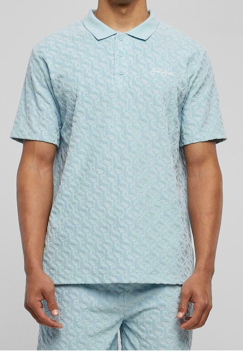 Polo bleu clair à manches courtes avec un motif texturé présentant un détail de logo subtil et une patte à trois boutons. Confectionné en tissu doux.