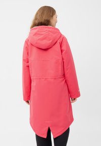 Abrigo de agua rosa con capucha, con un diseño de longitud media, cintura ajustable con cordón y dobladillo dividido. Textura suave, ajuste casual.