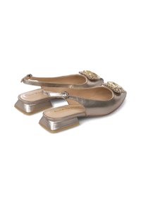 Zapatos slingback metálicos dorados con un bajo tacón cuadrado, que presentan adornos decorativos en la puntera y una suave textura de cuero.