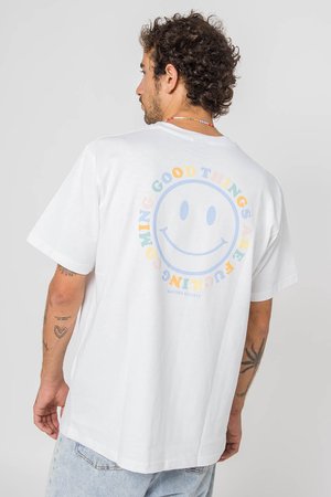 White cotton t-shirt featuring a large smiley face graphic on the back, with multicolored text reading "GOOD THINGS ARE COMING." Slightly loose fit.