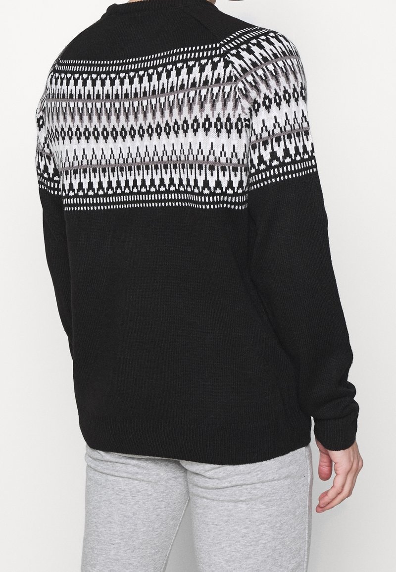 Černý pletený svetr s bílým a šedým geometrickým vzorem na horní části zad a ramenou. Hladké manžety a spodní lem.