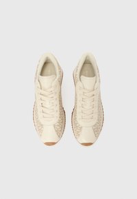 Μπεζ αθλητικά παπούτσια με λείο πάνω μέρος από δέρμα, υφασμένα πλαϊνά πάνελ και υφασμένη σόλα από καουτσούκ. Διαθέτουν κορδόνια στο ίδιο χρώμα και μινιμαλιστικό σχεδιασμό.