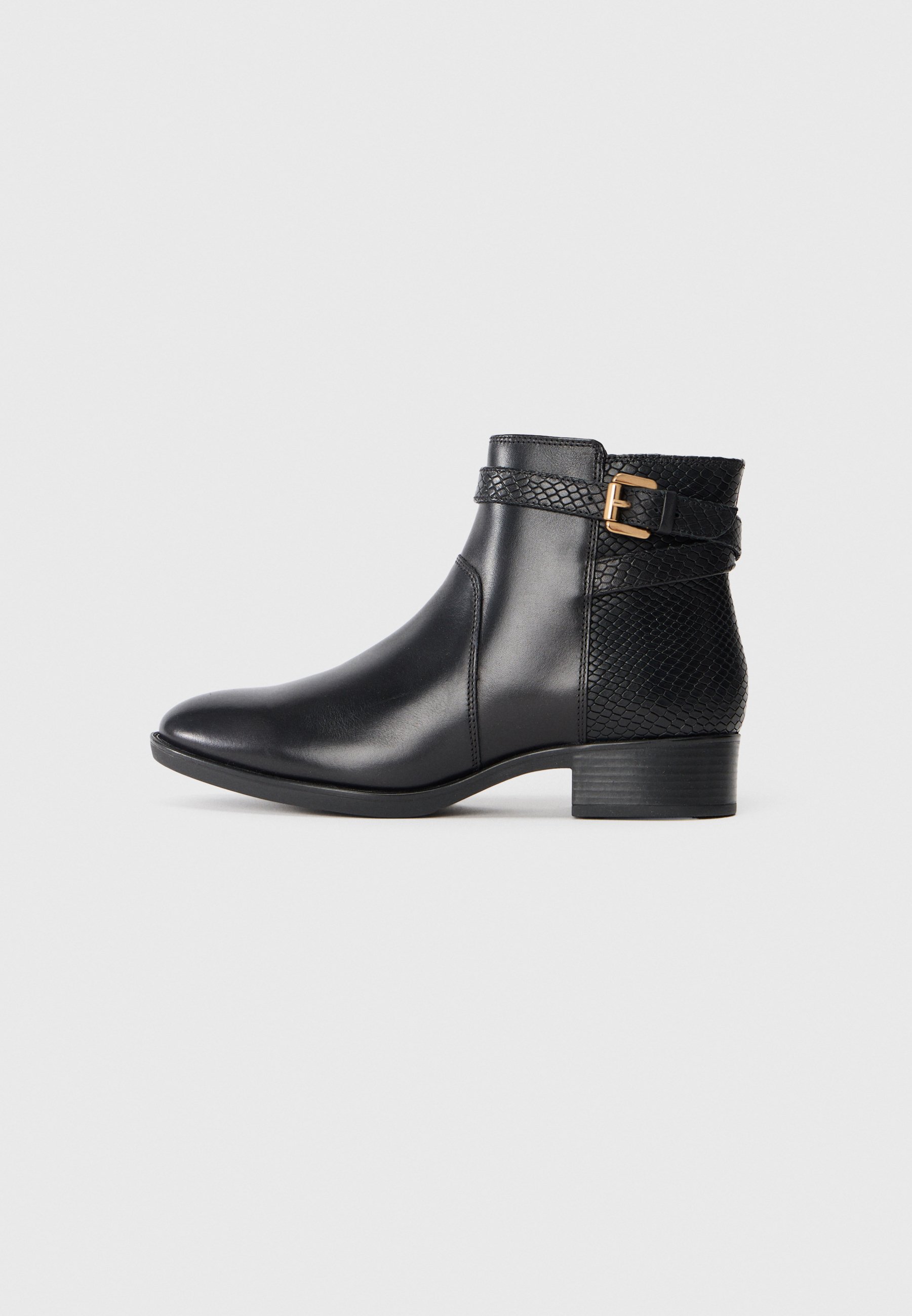 Bottines en cuir noir avec une finition lisse, un panneau arrière texturé et une sangle décorative avec une boucle dorée. Talon bas.