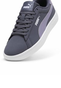 Tamsiai pilki odiniai sportbačiai su šviesiai violetinėmis detalėmis, plokščiu guminio pado, apvaliu nosiu ir baltais logotipais šone bei liežuvėlyje.