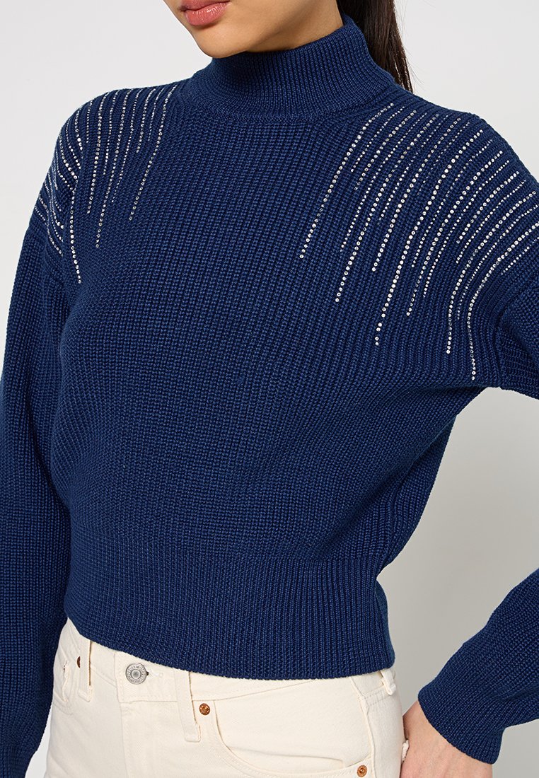Maglione lavorato a maglia blu navy con colletto alto, caratterizzato da un motivo testurizzato e dettagli in strass argentati lungo le spalle.