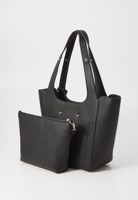 Zwarte leren tote bag met textuur en twee handvatten, bevat een kleine afneembare ritszak. Accenten zijn kleine metalen studs.