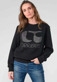 Sweatshirt noir avec un col rond, arborant un texte de logo gris métallique "cerises" dans une police audacieuse et moderne. Texture de tissu douce.