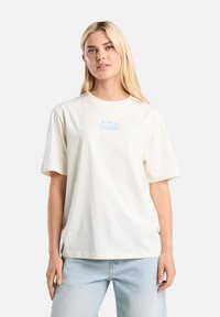 Cream-colored cotton t-shirt with short sleeves and a relaxed fit. Features blue text and graphics centered on the chest.