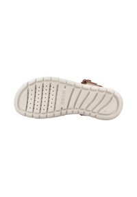 Suela de goma blanca con ranuras texturizadas y perforaciones para tracción. Correa superior marrón parcialmente visible con detalle de hebilla.