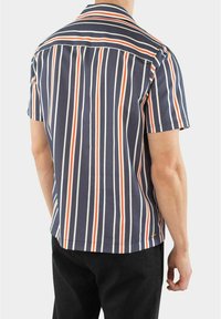 Kortærmet skjorte i marineblå med lodrette striber i rød, hvid og orange, med krave og en skræddersyet pasform for et struktureret udseende.