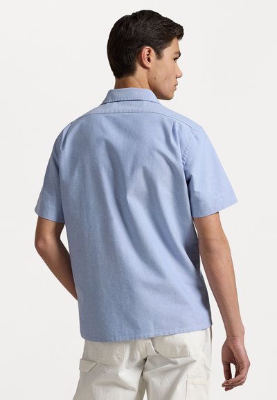 Kortärmad, ljusblå bomullsskjorta med spridd krage. Slät textur, rak fåll och subtila sömnadsdetaljer vid axlarna.