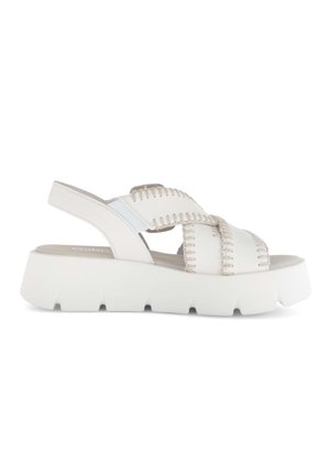 Sandale à plateforme blanche avec semelle épaisse rainurée, brides croisées tissées et bride arrière réglable, présentée sur un fond blanc.