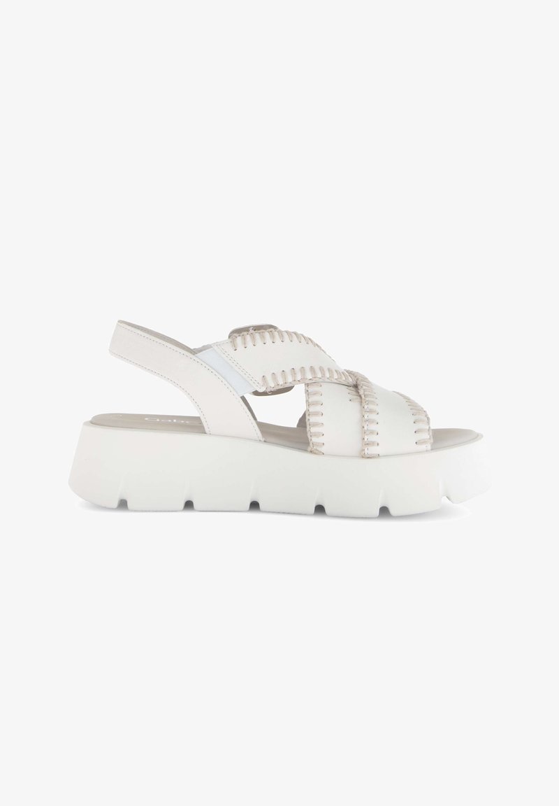 Weiße Plateausandale mit dicker, geriefter Sohle, geflochtenen Kreuzriemen und verstellbarem Riemen hinten, dargestellt auf weißem Hintergrund.