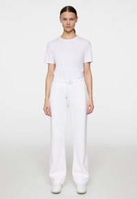 Vit bomullströja med korta ärmar och rundad halsringning, som matchas med löst sittande vita sweatpants med justerbar dragsko.