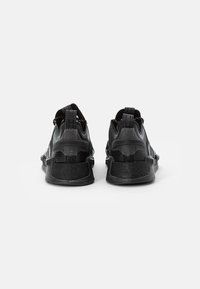 Svarta sportskor med en texturerad ovandel, nätpaneler och en fast hälkappa. Inkluderar ett dragband och gummisula för grepp.