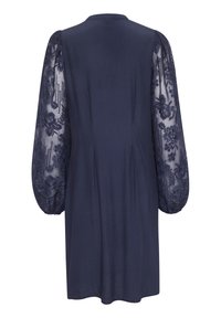 Marinblå klänning med en slät tygkropp och genomskinliga spetspuffärmar med blommönster. Rund halsringning med en avslappnad passform.