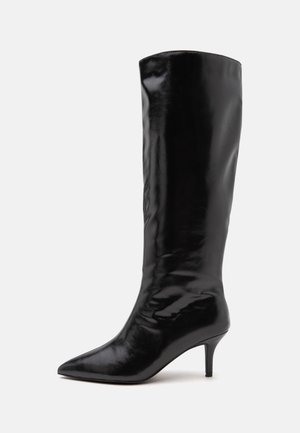 Botte noire en cuir montant jusqu'au genou, avec un bout pointu et un talon aiguille fin de hauteur moyenne, présentée sur un fond uni.