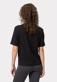T-shirt nero a maniche corte realizzato in morbido cotone misto. Vestibilità rilassata con scollatura rotonda e superficie liscia. Vista posteriore mostrata.