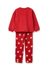 Sudadera roja de algodón con mangas largas combinada con leggings rojos con grandes lunares beige, ambos con una textura suave.