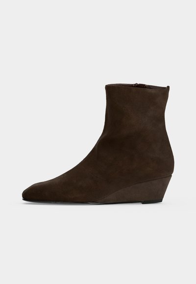 Bottine compensée en daim brun foncé montant à la cheville, avec un bout légèrement pointu et une texture lisse sur fond uni.
