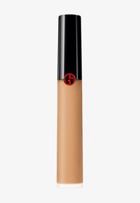 Foundation i en klar tube med en matt beige væske, svart hette og rødt logo. Slank tekstur, sylinderformet, cirka 15 cm høy.