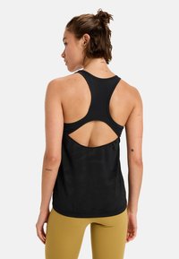 Svart sporttopp med racerback-design och öppen rygg. Mjuk, slät tyg med en lätt glans, i kombination med figurnära leggings.