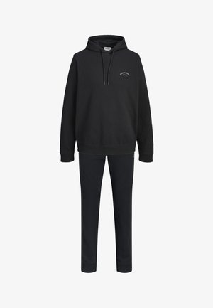 Czarna bluza z kapturem z przodu z kieszenią i sznurkami, w połączeniu z dopasowanymi czarnymi spodniami dresowymi z mankietami na nogawkach.