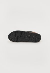 Čierna gumová podrážka s textúrovaným vzorom a logom Nike. Obsahuje dizajn podporujúci oblúk a cik-cak vzor pre trakciu.