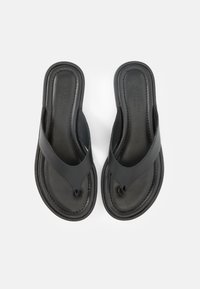 Ζευγάρι μαύρα δερμάτινα σανδάλια τύπου σαγιονάρα με επενδυμένες σόλες και φαρδιές λουράκια, φωτογραφημένα από πάνω σε λευκό φόντο.