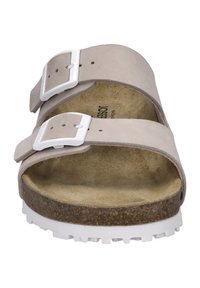 Sandal in suede grigio chiaro con due fibbie bianche regolabili, un plantare in sughero e una suola in gomma bianca con battistrada testurizzato.