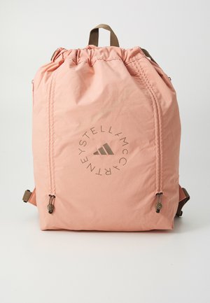 Sac à dos rose à cordon en tissu léger, avec un logo circulaire gris, des bretelles ajustables beige et une texture lisse.