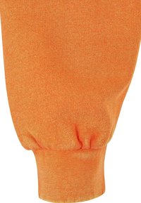 Gros plan sur la manche d'un pull en tricot orange avec un détail de poignet froncé.