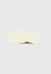 Σόλα λευκού αθλητικού παπουτσιού με υφή πέλματος σε απλό ανοιχτό γκρι φόντο.