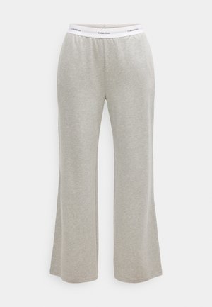 Pantalons de survêtement évasés gris en tissu doux, dotés d'une taille élastique blanche avec le logo "Calvin Klein" dans un motif continu.