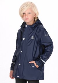 Jūras spēku ūdensnecaurlaidīgs žakets ar kapuci, kontrastējošām baltām pogām, divām sānu kabatām un pelēku logo kreisajā krūtī. Gluda tekstūra.