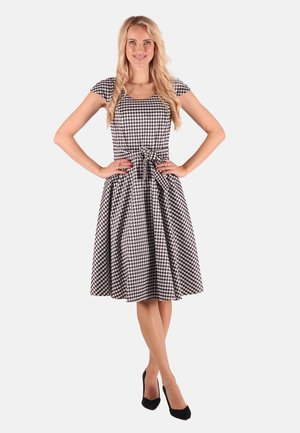 Schwarzes und weißes Gingham-Kleid mit kurzen Ärmeln, tailliertem Oberteil und ausgestellt Rock; hat eine gebundene Taille und saubere Nähte.