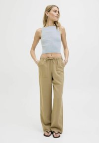 Svijetloplavi rebrasti crop top i bež široke hlače s dva prednja džepa i elastičnim pojasom s vezicom. Model nosi crne japanke.