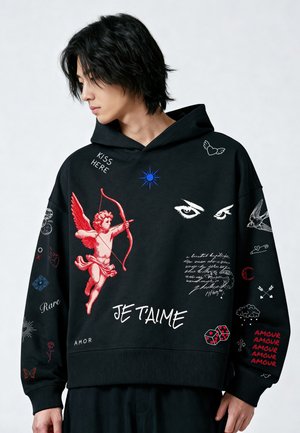 Jong persoon met zwart haar die een zwarte hoodie draagt met een rode cupido, witte ogen, tekstzinnen en kleine grafische symbolen.