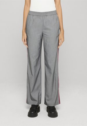 Pantalones grises de pierna ancha con cintura elástica y franjas laterales en burdeos y blanco, usados con zapatos negros gruesos por una persona de pie.