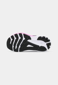 Black and white athletic shoe sole with flexible grooves, pink accents, and textured black rubber for grip. Designed for performance and stability.