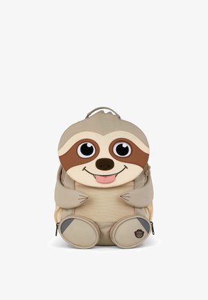 Beige children's backpack shaped like a smiling sloth with big eyes, sticking out tongue, arms, and legs with zippered pockets.