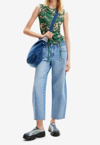 Vihreä kukallinen hihaton toppi, vaaleat leveälahkeiset farkut, sininen denimitaskulaukku ja siniset liukastettavat kengät mustilla pohjilla.