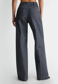 Dark gray wide-leg trousers made from textured fabric, featuring a waistband with belt loops, two back pockets, and a straight cut.