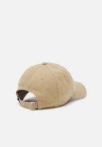 Boné de beje em algodão com faixa ajustável em fivela de metal e ilhós de ventilação, apresentado de costas sobre um fundo branco.