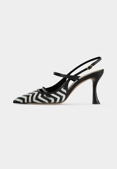 Escarpin à talon haut à bout pointu avec bride arrière, motif zigzag noir et blanc, fines lanières et boucle dorée sur fond blanc.