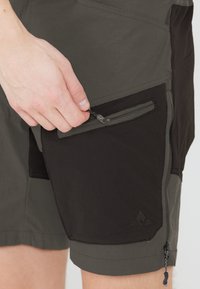 Miestne šortky s čiernym a tmavošedým farebným schémou, s vreckom na zips a detailom nastaviteľného hardvéru. Ľahký, priedušný materiál.