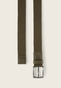 Ceinture tissée vert olive avec une partie en cuir et une boucle en métal argenté, mettant en avant un motif texturé et un design flexible et réglable.