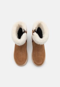 Ruske nubuk ankle sa cilijastim belim krznom, crni unutrašnji oblog, zaobljen vrh i teksturisani đon.