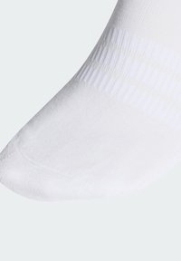 Chaussette blanche à la cheville avec une texture lisse, comportant une section supérieure côtelée. L'orteil est arrondi, et le design global est simple et uniforme.