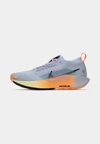 Zapatilla de running azul claro con un upper texturizado, cordones rosas y logo negro. Presenta una suela en degradado de naranja y amarillo para mayor tracción.